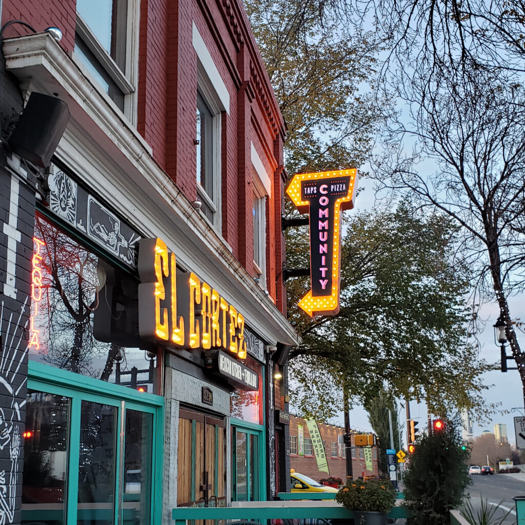 A neon sign points to Community Taps and Pizza