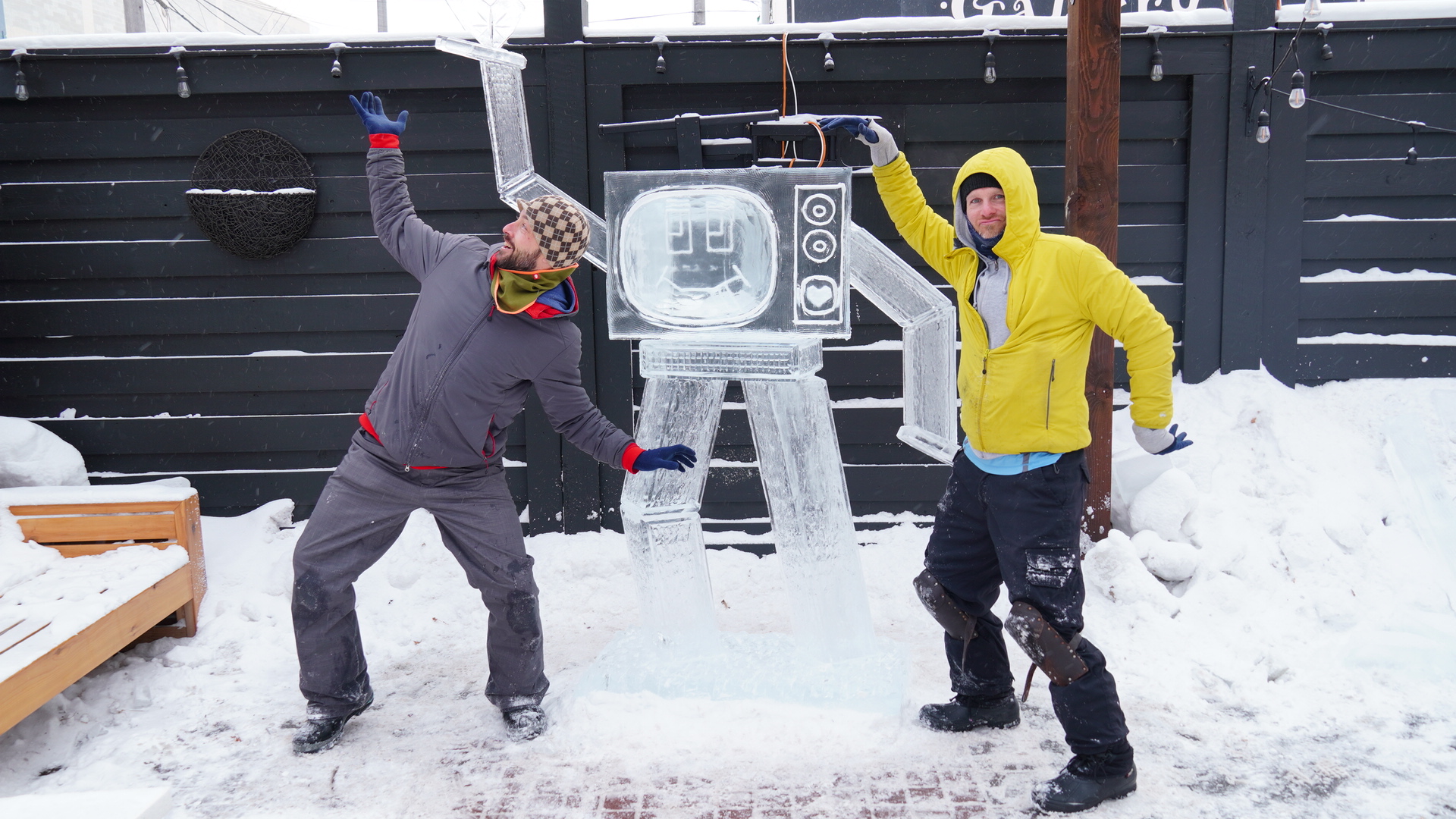 Two ice carvers pose with their arms pointed out in both directions mimicking their TV man carving